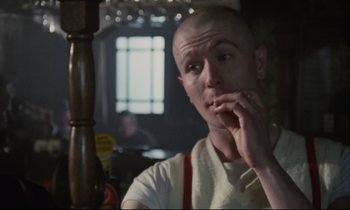 Movie still from “Meantime” (1983), directed by Mike Leigh – A man with a shaved head sitting at a table in a restaurant; Close Up shot, Low angle