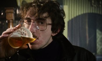 Movie still from “Meantime” (1983), directed by Mike Leigh – A man drinking a glass of beer while wearing glasses; Close Up shot, Low angle