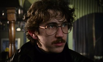 Movie still from “Meantime” (1983), directed by Mike Leigh – A person wearing glasses and a jacket; Close Up shot, Low angle