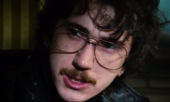 Movie still from “Meantime” (1983), directed by Mike Leigh – A person wearing glasses and a mustache; Close Up shot, Low angle