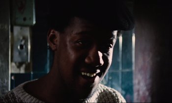 Movie still from “Meantime” (1983), directed by Mike Leigh – A person with a smile on their face; Close Up shot, Low angle