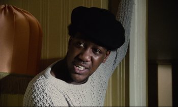 Movie still from “Meantime” (1983), directed by Mike Leigh – A man wearing a black hat leaning against a wall; Close Up shot, Low angle