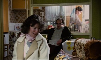 Movie still from “Meantime” (1983), directed by Mike Leigh – A woman and a man sitting in front of a window; Medium shot, Over the shoulder angle