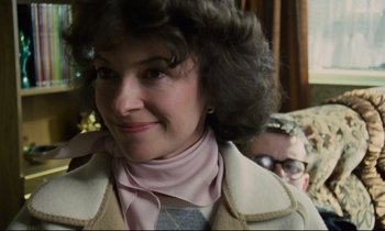 Movie still from “Meantime” (1983), directed by Mike Leigh – An older woman wearing a jacket and a pink shirt; Close Up shot, Over the shoulder angle
