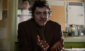Movie still from “Meantime” (1983), directed by Mike Leigh – A man sitting in front of a window with his hands clapping; Close Up shot, Low angle