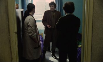 Movie still from “Meantime” (1983), directed by Mike Leigh – A group of people standing in front of a window; Medium shot, Over the shoulder angle