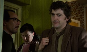 Movie still from “Meantime” (1983), directed by Mike Leigh – A man and a woman standing next to each other in a room; Medium shot, Over the shoulder angle