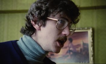 Movie still from “Meantime” (1983), directed by Mike Leigh – A man with a beard and glasses is looking at the camera; Close Up shot, Low angle