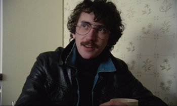 Movie still from “Meantime” (1983), directed by Mike Leigh – A man in a leather jacket and glasses; Close Up shot, Low angle