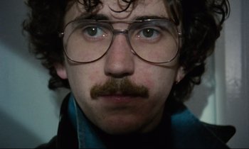 Movie still from “Meantime” (1983), directed by Mike Leigh – A person wearing glasses and a mustache; Close Up shot, High angle