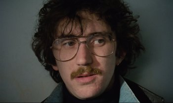 Movie still from “Meantime” (1983), directed by Mike Leigh – A person wearing glasses and a beard; Close Up shot, Low angle