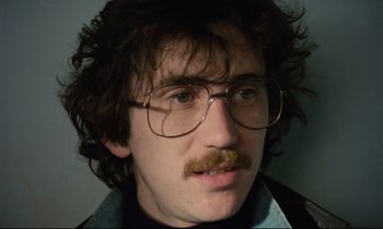 Movie still from “Meantime” (1983), directed by Mike Leigh – A person wearing glasses and a beard; Close Up shot, Low angle