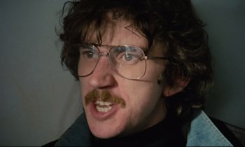 Movie still from “Meantime” (1983), directed by Mike Leigh – A person wearing glasses and a mustache; Close Up shot, Low angle