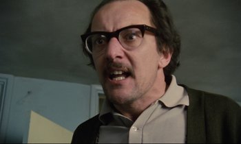 Movie still from “Meantime” (1983), directed by Mike Leigh – A person wearing glasses and a jacket; Close Up shot, Low angle