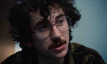 Movie still from “Meantime” (1983), directed by Mike Leigh – A man with a beard and glasses is looking at the camera; Close Up shot, Low angle