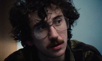 Movie still from “Meantime” (1983), directed by Mike Leigh – A man with a mustache wearing glasses and a plaid shirt; Close Up shot, Low angle