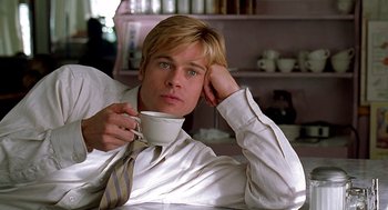 Movie still from “Meet Joe Black” (1998), directed by Martin Brest – A man holding a coffee cup while sitting on a table; Medium shot, Low angle