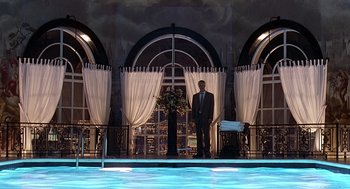 Movie still from “Meet Joe Black” (1998), directed by Martin Brest – A man standing in front of an indoor swimming pool; Extreme Wide shot, Low angle