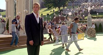 Movie still from “Meet Joe Black” (1998), directed by Martin Brest – A man in a suit and tie standing in front of a crowd of onlookers; Wide shot, Over the shoulder angle