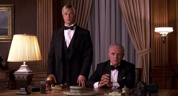Movie still from “Meet Joe Black” (1998), directed by Martin Brest – Two men in tuxedos sitting at a table in a room; Medium shot, Low angle