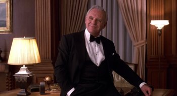 Movie still from “Meet Joe Black” (1998), directed by Martin Brest – A man in a tuxedo sitting on a table; Medium shot, Low angle