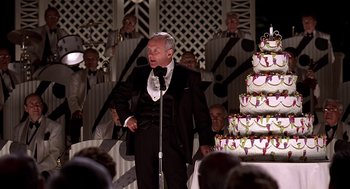 Movie still from “Meet Joe Black” (1998), directed by Martin Brest – An older man in front of a large cake; Medium shot, Over the shoulder angle