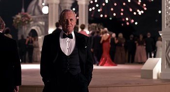 Movie still from “Meet Joe Black” (1998), directed by Martin Brest – An older man in a tuxedo standing in front of a crowd of onlookers at an event; Medium shot, Over the shoulder angle