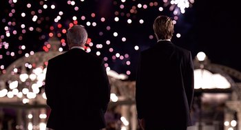 Movie still from “Meet Joe Black” (1998), directed by Martin Brest – Two men in suits are standing in front of lights at night; Medium shot, Over the shoulder angle