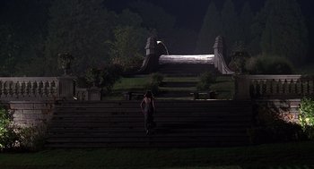 Movie still from “Meet Joe Black” (1998), directed by Martin Brest – A woman standing on a set of steps at night; Extreme Wide shot, High angle