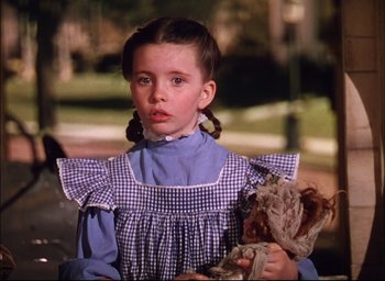 Movie still from “Meet Me in St. Louis” (1944), directed by Vincente Minnelli – A little girl in a blue and white dress holding a doll; Close Up shot, Low angle