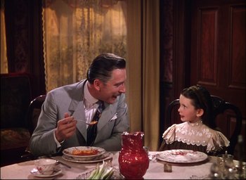 Movie still from “Meet Me in St. Louis” (1944), directed by Vincente Minnelli – A man sitting at a dinner table with a little girl; Medium shot, Over the shoulder angle