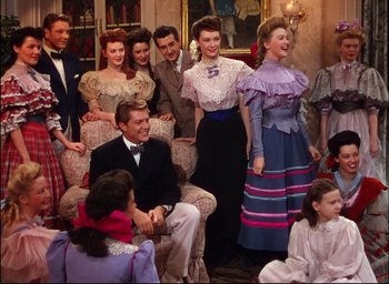 Movie still from “Meet Me in St. Louis” (1944), directed by Vincente Minnelli – A group of people sitting and standing in a living room; Medium shot, High angle
