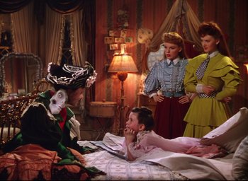 Movie still from “Meet Me in St. Louis” (1944), directed by Vincente Minnelli – A group of people standing around a bed; Medium shot, High angle