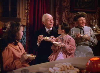 Movie still from “Meet Me in St. Louis” (1944), directed by Vincente Minnelli – An old man holding a plate of food near a group of people; Medium shot, High angle