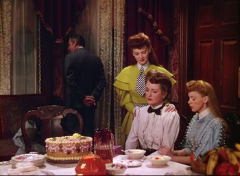 Movie still from “Meet Me in St. Louis” (1944), directed by Vincente Minnelli – A group of people sitting around a table with a cake; Medium shot, High angle