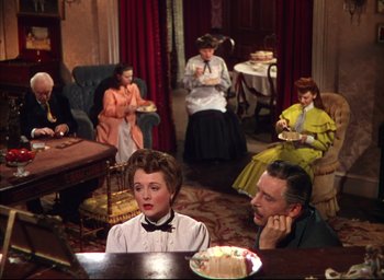 Movie still from “Meet Me in St. Louis” (1944), directed by Vincente Minnelli – A group of people sitting at a table in a living room; Medium shot, High angle