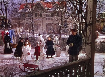 Movie still from “Meet Me in St. Louis” (1944), directed by Vincente Minnelli – A group of people standing in the snow next to a house; Extreme Wide shot, High angle