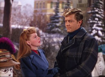 Movie still from “Meet Me in St. Louis” (1944), directed by Vincente Minnelli – A man and a woman standing next to each other in front of trees; Medium shot, Over the shoulder angle