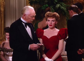 Movie still from “Meet Me in St. Louis” (1944), directed by Vincente Minnelli – An old man and a woman in a red dress; Medium shot, Over the shoulder angle