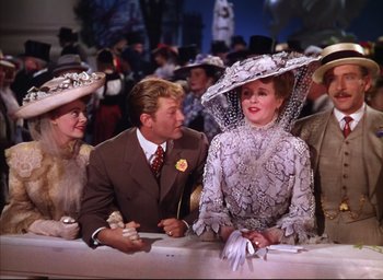 Movie still from “Meet Me in St. Louis” (1944), directed by Vincente Minnelli – A group of people sitting around a table wearing fancy hats; Medium shot, Over the shoulder angle