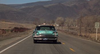 Movie still from “Melvin and Howard” (1980), directed by Jonathan Demme – An old car driving down a road in the middle of the day; Wide shot, Low angle