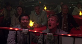 Movie still from “Melvin and Howard” (1980), directed by Jonathan Demme – A group of people sitting in a room with lights on; Medium shot, Low angle