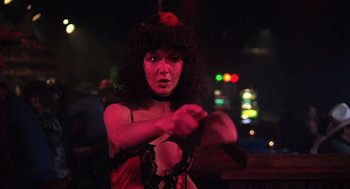 Movie still from “Melvin and Howard” (1980), directed by Jonathan Demme – A woman in a black dress is holding a whip; Medium shot, Low angle