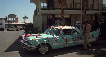 Movie still from “Melvin and Howard” (1980), directed by Jonathan Demme – An old car decorated for a wedding with ribbons on the hood; Wide shot, Low angle