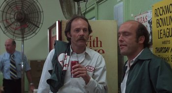 Movie still from “Melvin and Howard” (1980), directed by Jonathan Demme – A man holding a can of soda while standing next to another man; Close Up shot, Low angle
