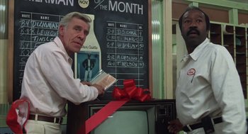 Movie still from “Melvin and Howard” (1980), directed by Jonathan Demme – Two men standing in front of a tv with a red bow on it; Medium shot, Low angle