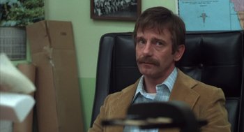 Movie still from “Melvin and Howard” (1980), directed by Jonathan Demme – A man sitting in an office chair wearing a brown jacket; Close Up shot, Over the shoulder angle