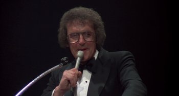 Movie still from “Melvin and Howard” (1980), directed by Jonathan Demme – A man in a tuxedo holding a microphone; Close Up shot, Low angle