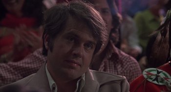 Movie still from “Melvin and Howard” (1980), directed by Jonathan Demme – A person sitting in front of a crowd; Close Up shot, Low angle
