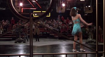 Movie still from “Melvin and Howard” (1980), directed by Jonathan Demme – A woman in a blue dress standing in front of an audience; Wide shot, Low angle
